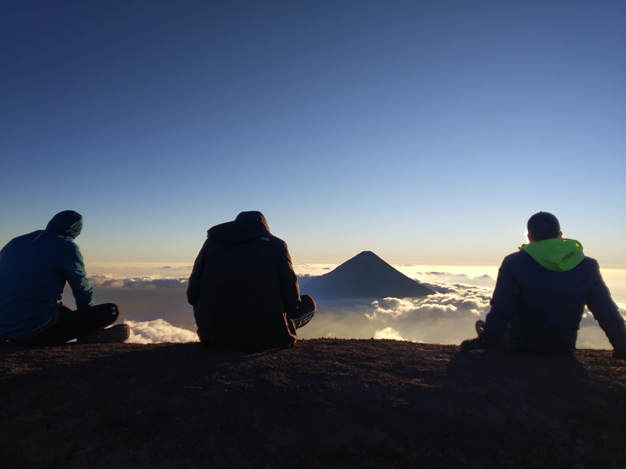 Hikers looking toward Fuego above a sea of clouds